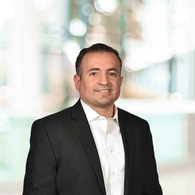 Portrait of a man in a suit in a blurred background.