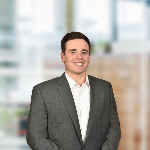 Man in suit smiling, professional portrait, office background.