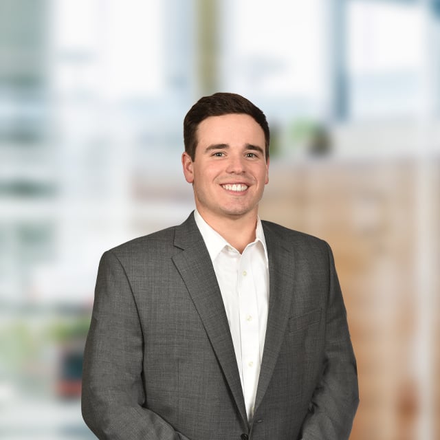 Man in suit smiling, professional portrait, office background.