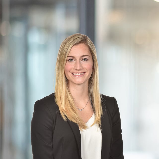 Blonde woman wearing a black blazer smiles.