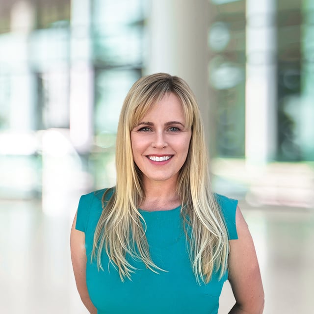 Woman with blonde hair smiling in an office setting.