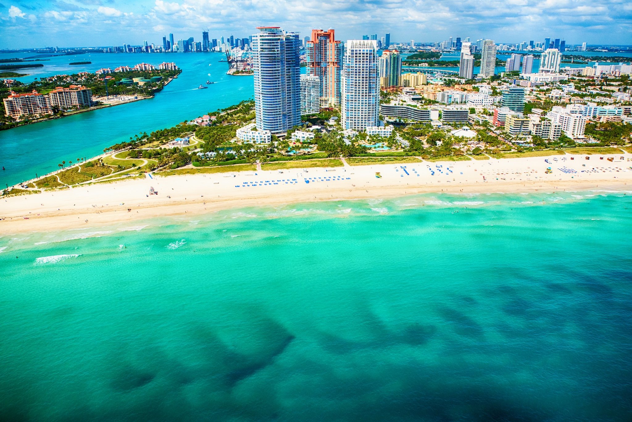 Aerial view of beach, buildings, and ocean. Blue water and clear sky.