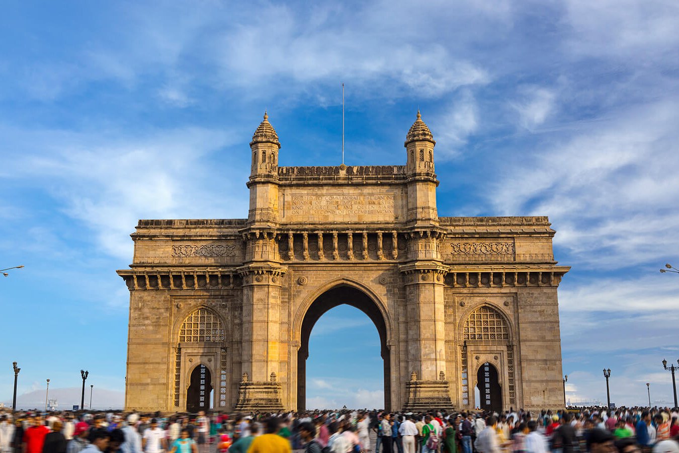 An archway with two towers with many people in front.