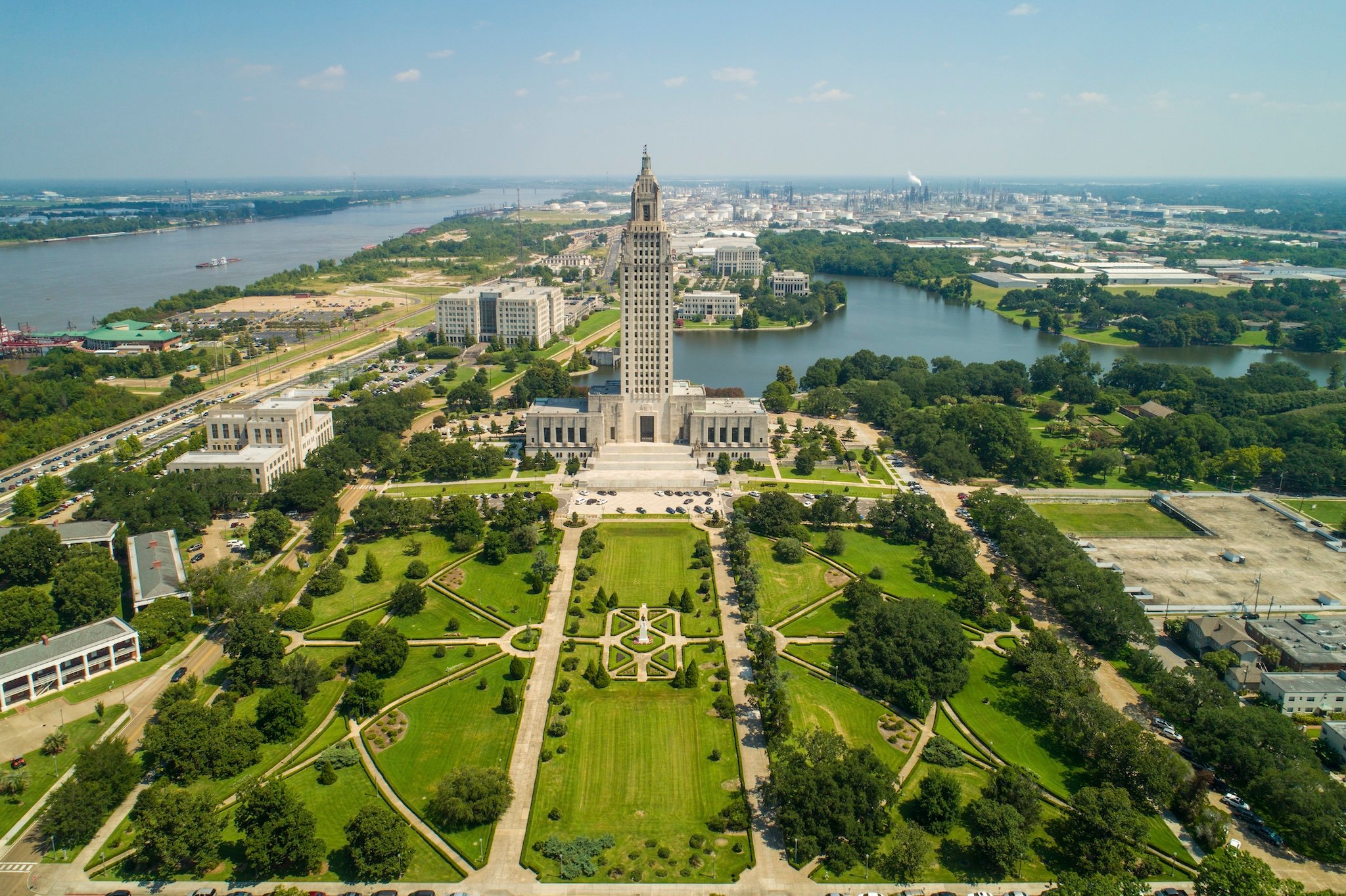 Aerial view of the Louisiana State Capitol building with surrounding park and river.