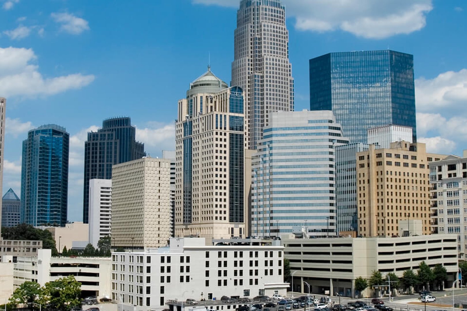 Downtown Charlotte skyscrapers under a blue sky with clouds.