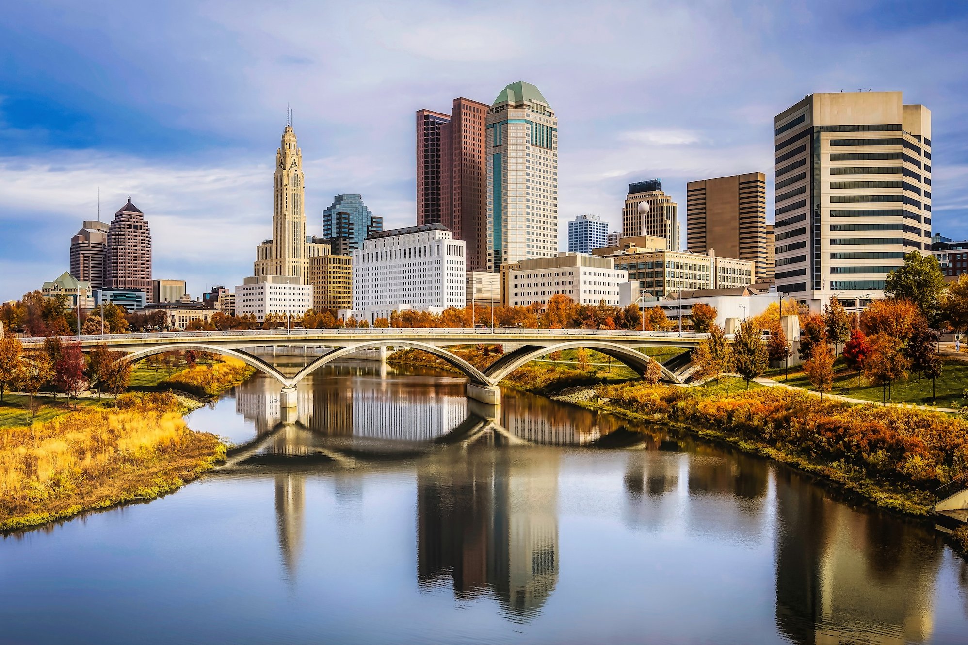 Columbus, Ohio skyline with bridge, river, and autumn foliage.