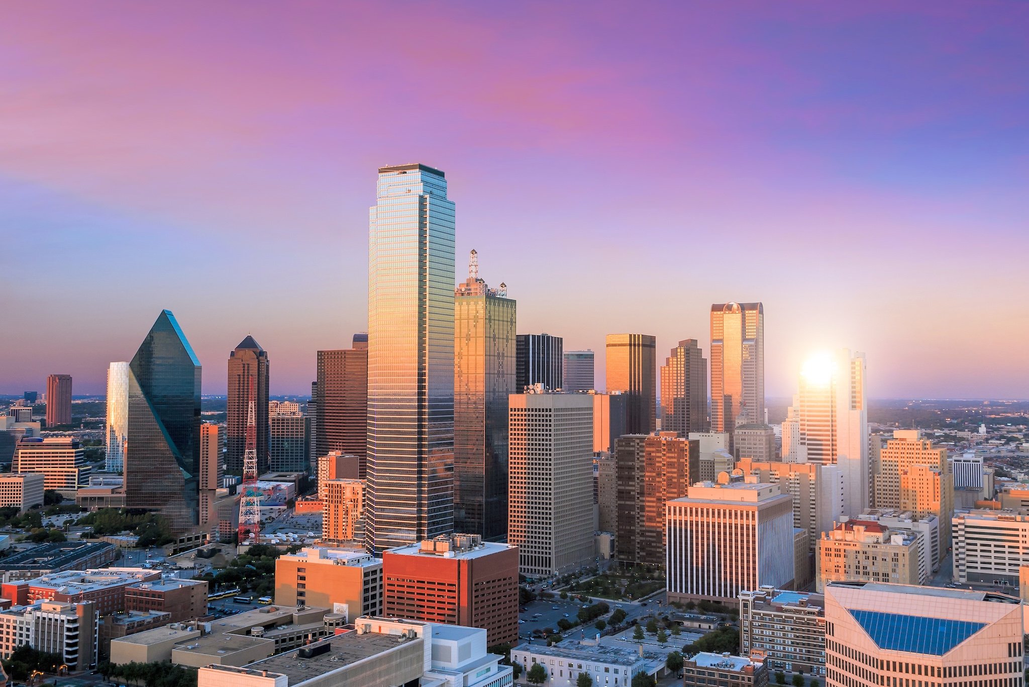 Aerial view of Dallas skyline at sunset, with the sun shining.
