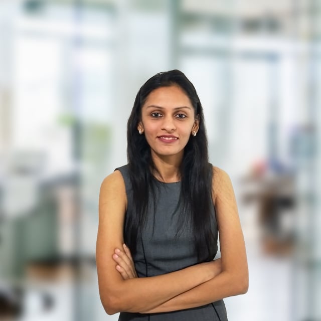 Woman with arms crossed, smiling in office setting.