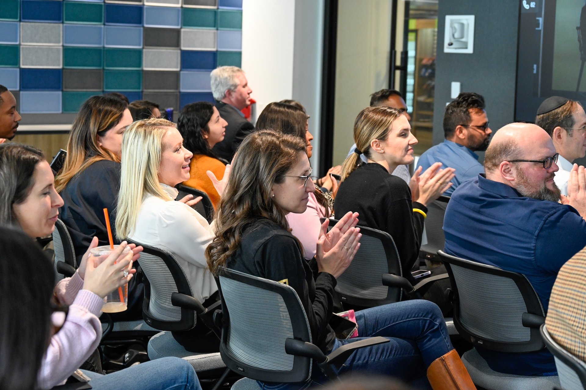 Group of people in a conference setting, clapping hands.