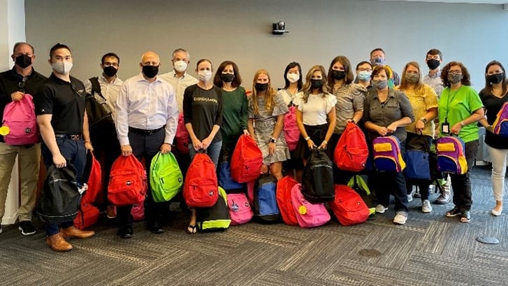 Group with backpacks, wearing masks, standing indoors.