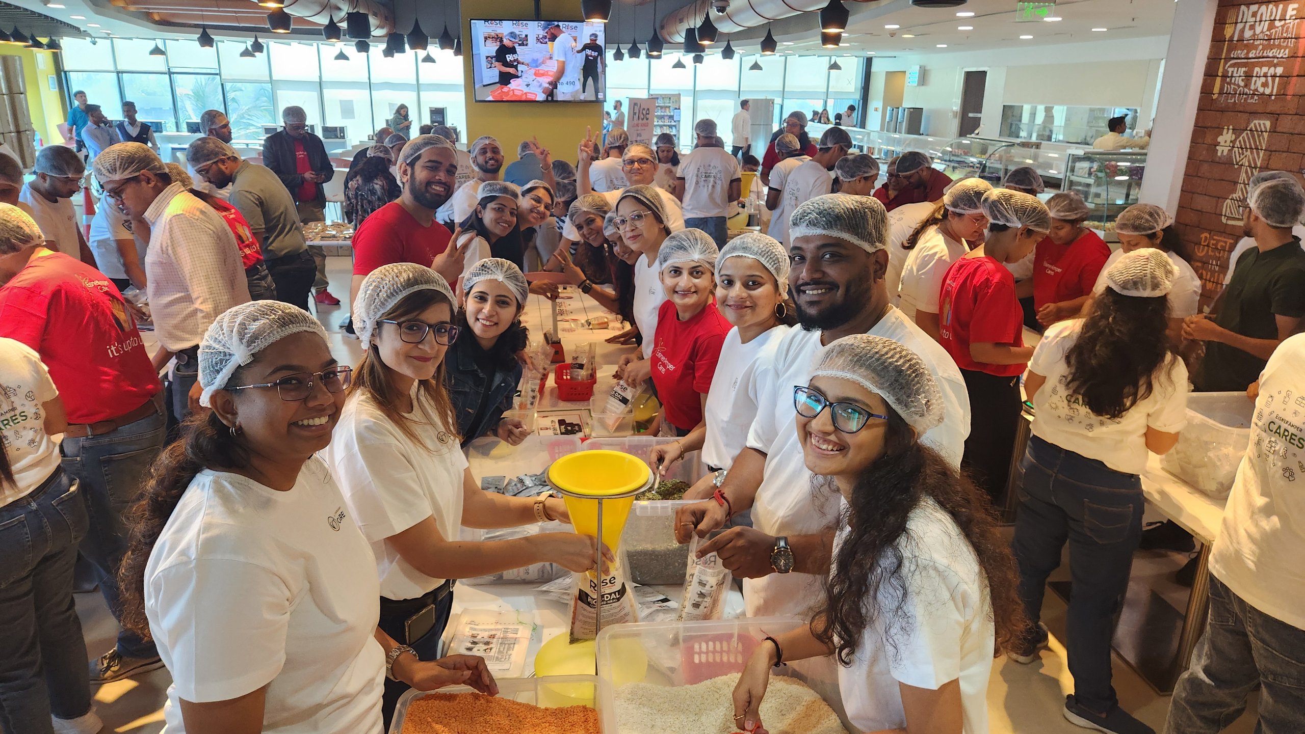 People in hairnets at an EisnerAmper Cares event, preparing food, smiling.