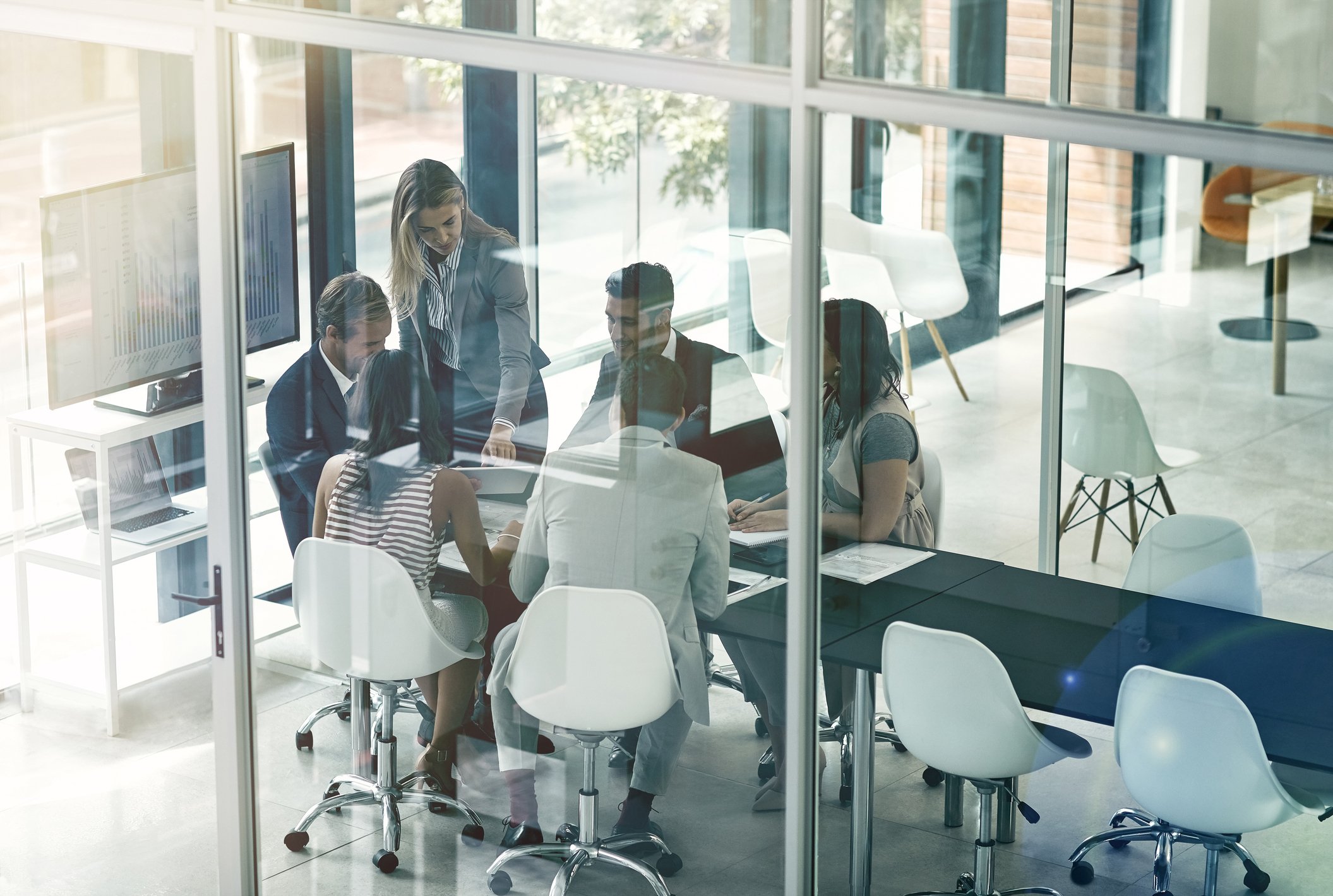 Group of people in meeting around table.  Reflections on glass.