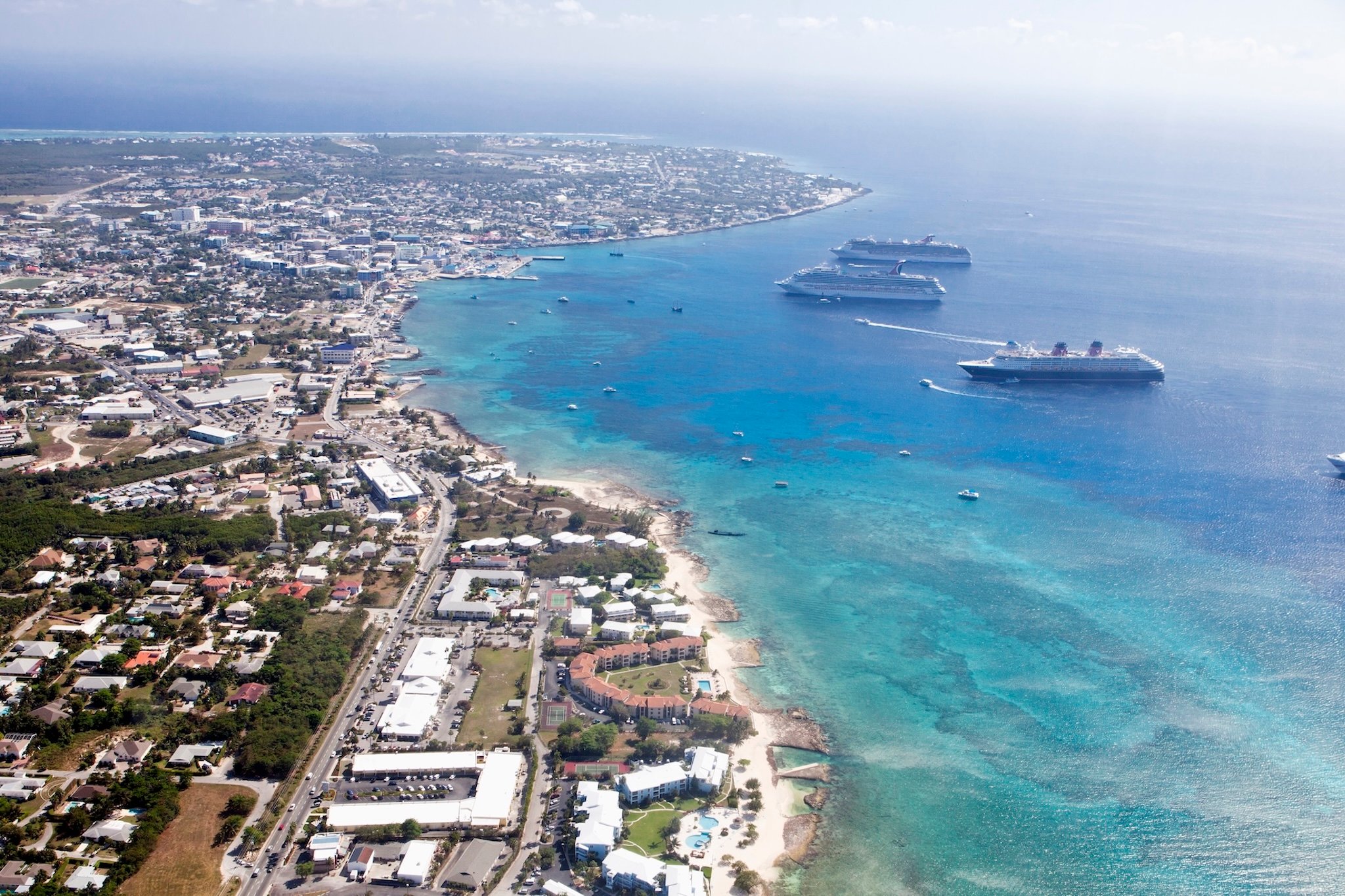 Aerial view of the Cayman Islands with cruise ships and coastal buildings.